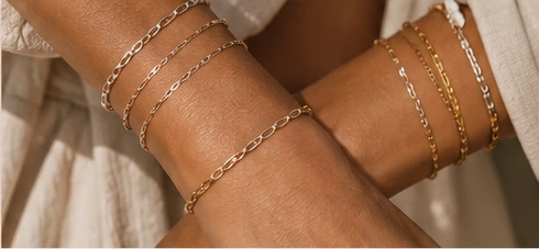 Two wrists with elegant gold and silver bracelets